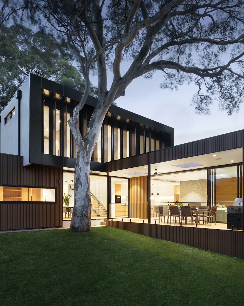 Modern architectural home at dusk with warm interior lighting